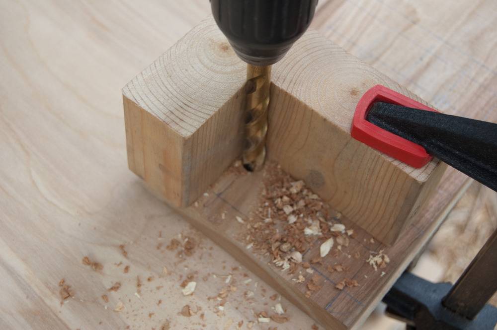 A power drill is drilling a hole into a wood block.