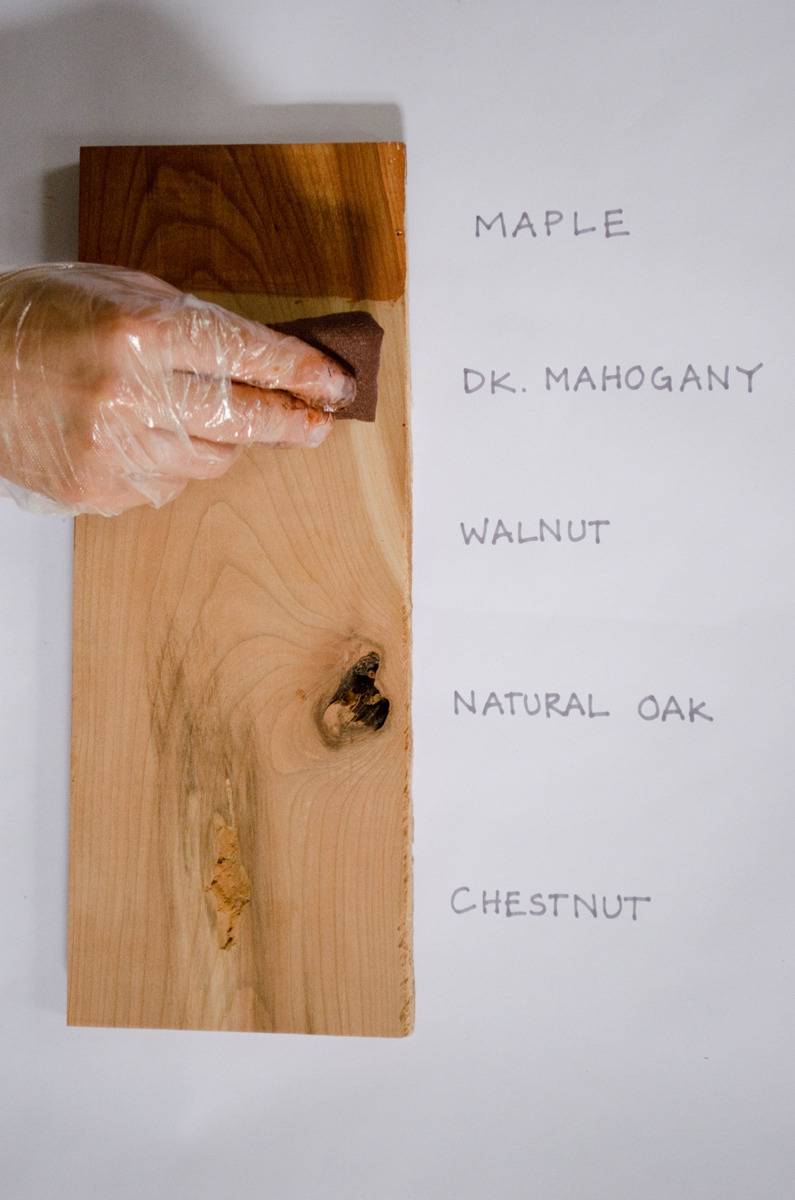 A person is wiping away stain on a piece of wood.