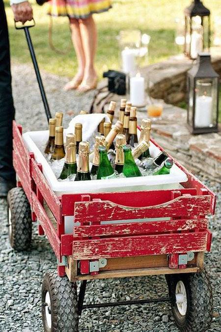 A person hauls wine in a little red wagon.