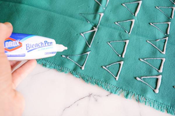 A piece of blue fabric has bleach liquid from a bleach pen.