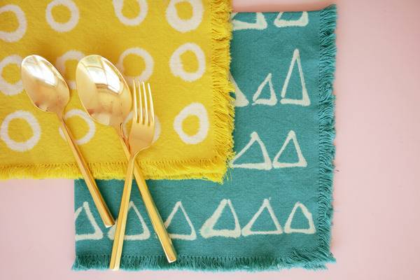 Golden silverware on top of yellow and turquoise place mats.