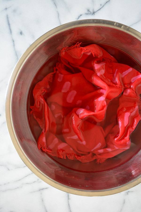 A wet piece of red fabric sits in a bowl on a table.