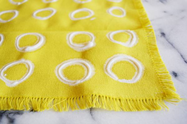A yellow frilly piece of cloth with rows of white rings on it.