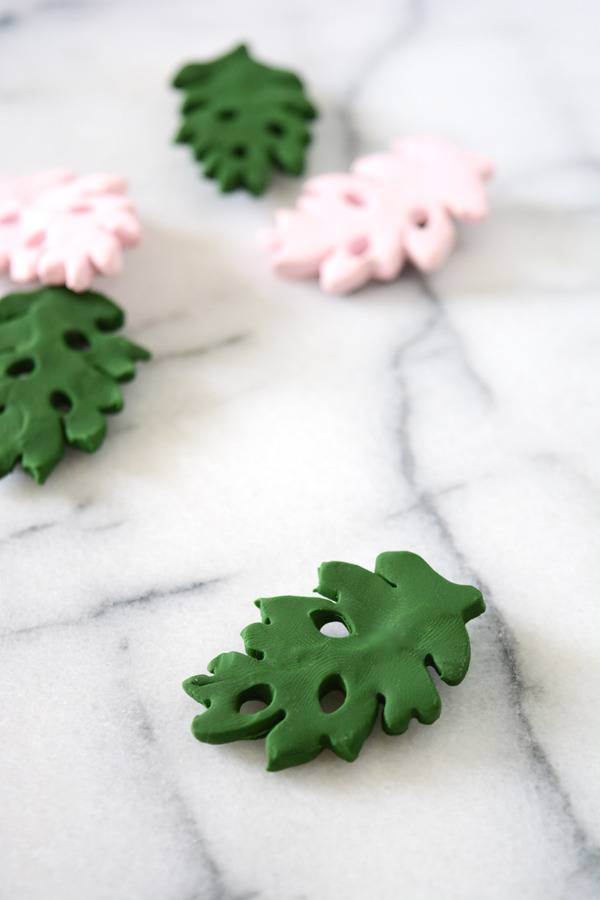Pink and green tropical leaf magnets sit on a marble countertop.