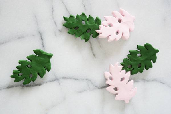 Three green clay trees and 2 pink clay trees laying on grey marble.