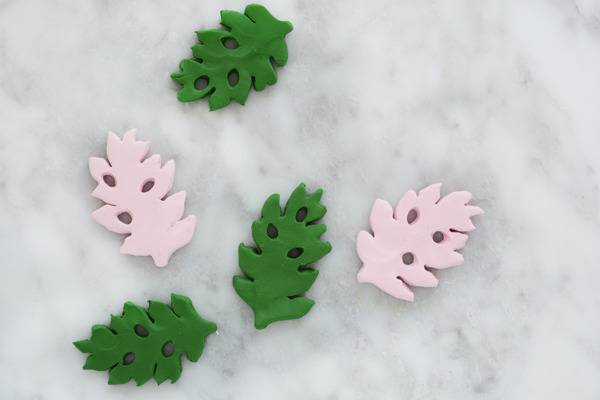Green and pink leaves are decorated on a white surface.