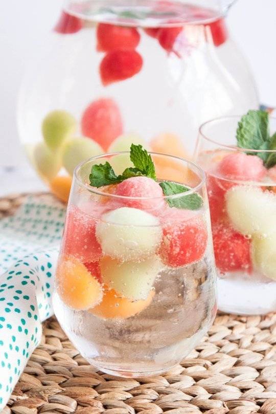Couple of glasses and pots full mixed fruits in water