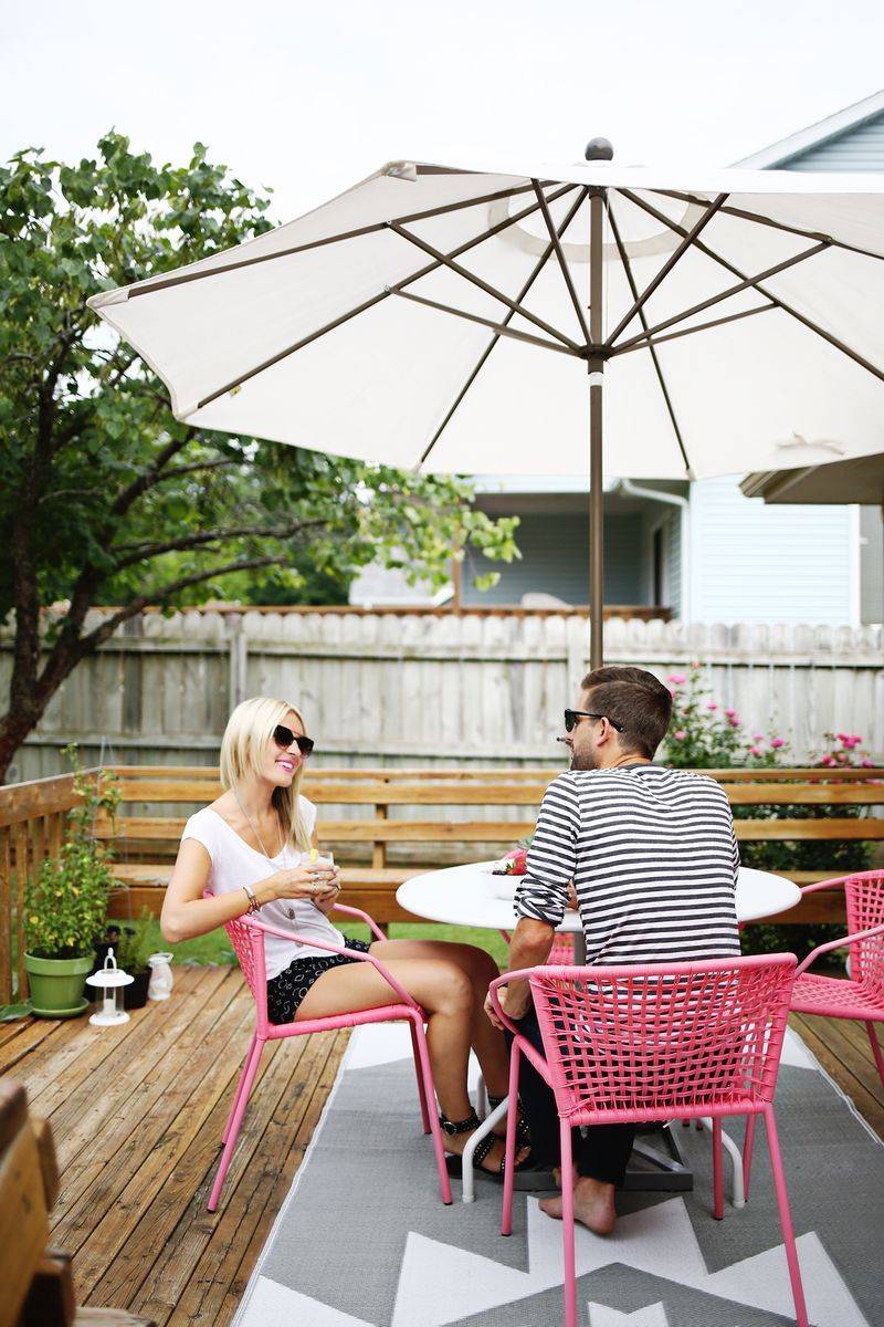 The young lady in the young man said the patio table under an umbrella in pink wire chairs.