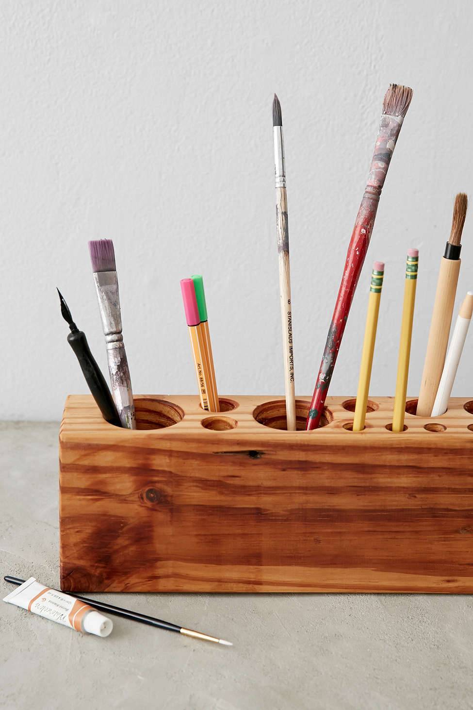 Paintbrushes are shown in a wooden container.