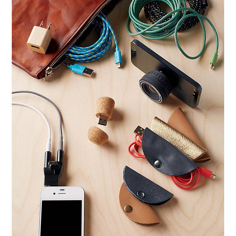 Cellphone chargers and accessories gathered together on top of a light piece of wood.