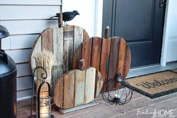 A welcome mat is sitting outside of a dark door near wooden cutouts.