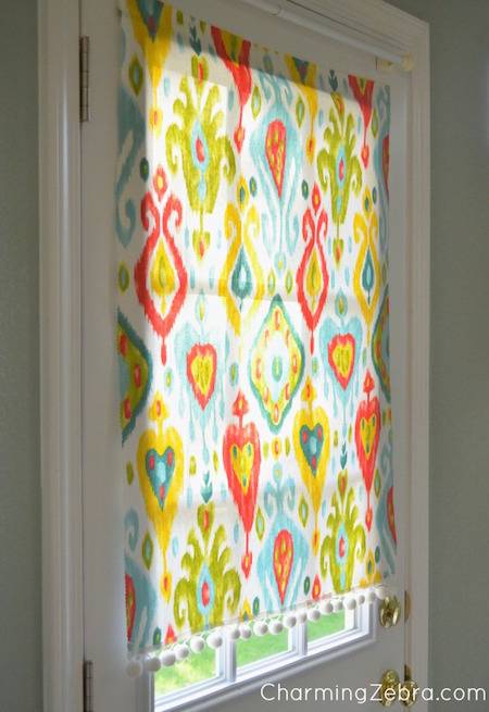 Kitchen entryway window cover with colorful designs of various shapes and sizes.