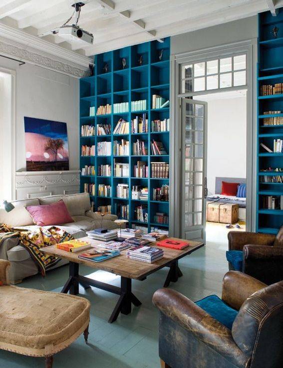 A living room has blue shelves on either side of the door.