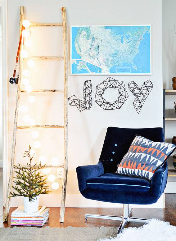 Wooden ladder with lights, blue colored rotating chair, potted plant and wall painting frame inside the house.
