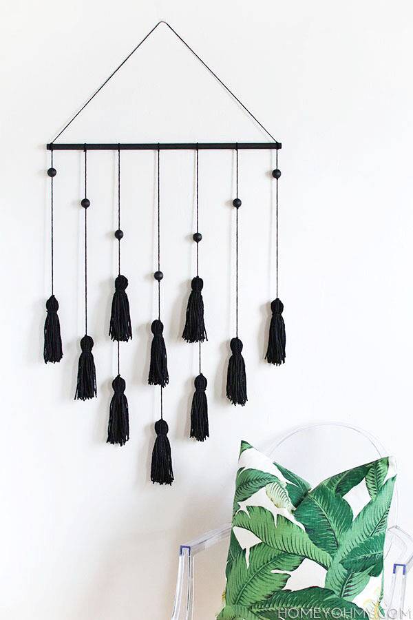 Black wooden owl rods hanging on a white wall next to a small green and white chair.