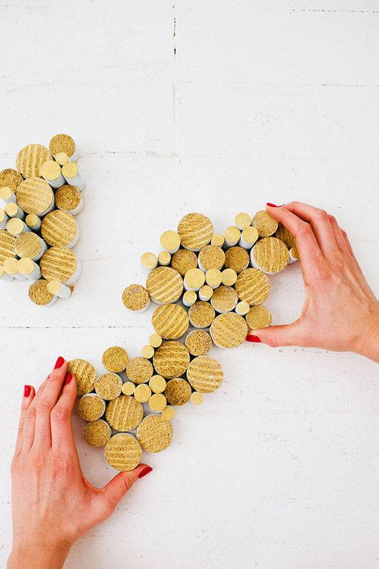 Hands surround an abstract grouping of wooden disks of varying sizes.