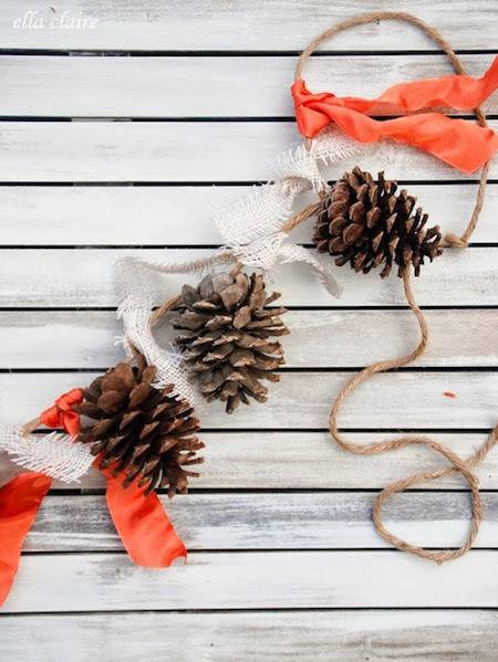 Pine cones are strung on a string with orange ribbons.
