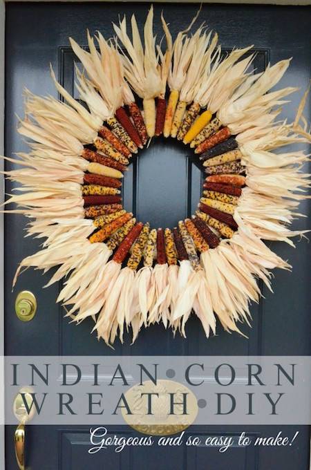 A wreath has been made out of corn and is hanging on a door.
