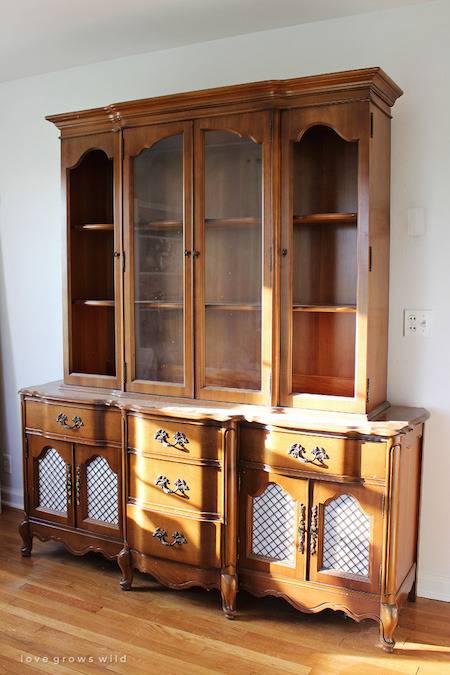 Medium brown wooden hutch with glass doors and four sections, atop a long cabinet with many drawers.