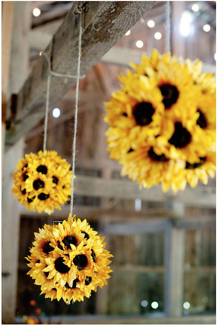 Yellow and brown sunflowers are dangling from strings.