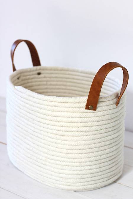 White laundry basket with brown handles.