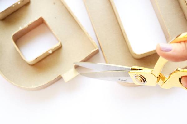 A pair of gold scissors ready to cut into a tan mold.