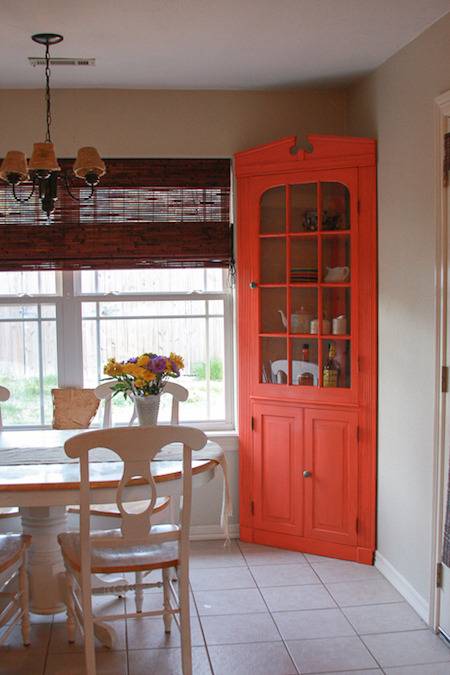 A white table and chairs in a dining room with an orange sideboard in the corner.