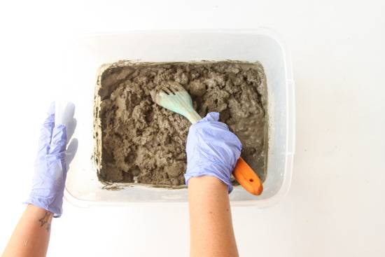 A person is preparing a concrete in a box with big spoon.