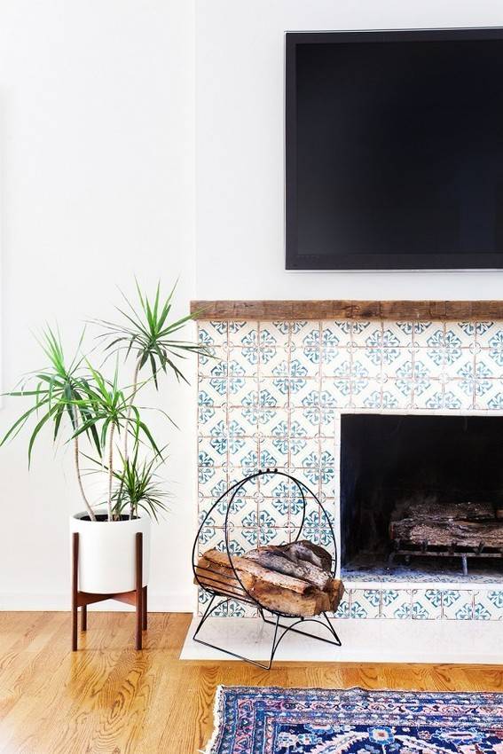 A television set hangs on the wall above a blue and white mantle piece.