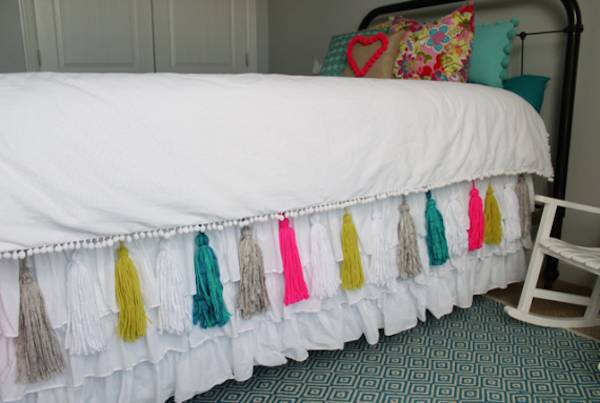 A single bed decked in white ruffle bedskirt.