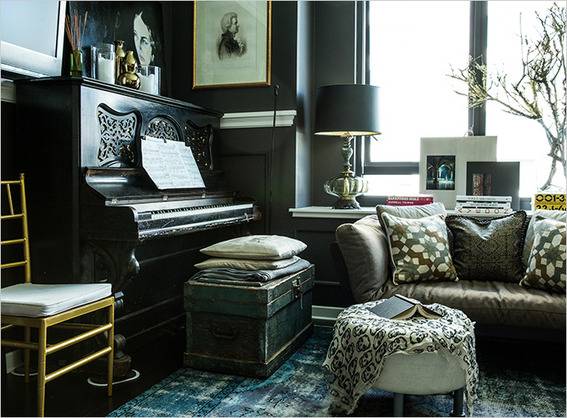 A dark colored living room has lots of furniture and a piano.