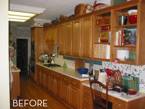 A before picture of a dated kitchen with brown wood cabinets and floors.