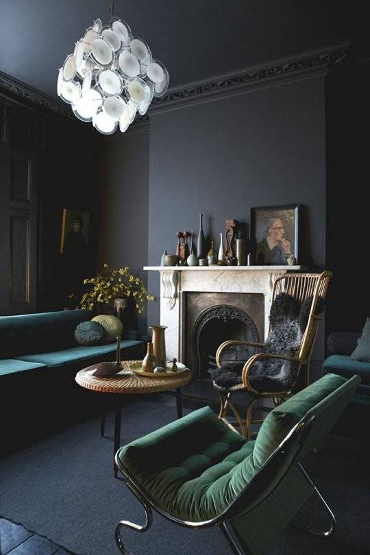 Dark colored chairs and a chandelier decoarate a dark room with dark walls.