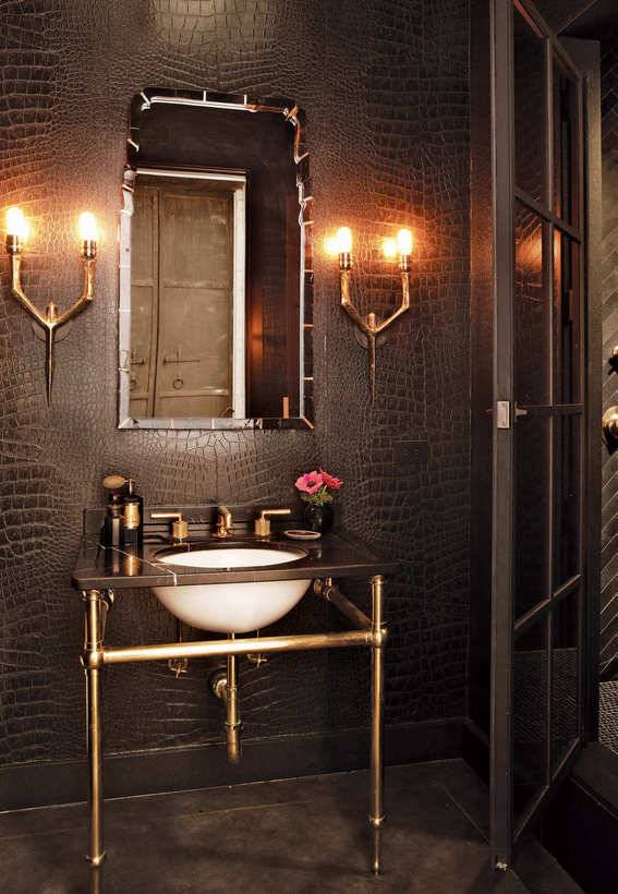 A sink on a copper base sits under a mirror in a dungeon themed bathroom.