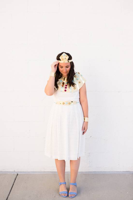 A lady in a white summer dress and purple shoes looks down at her shoes.