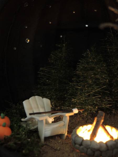 A white chair sits next to a lit fireplace.