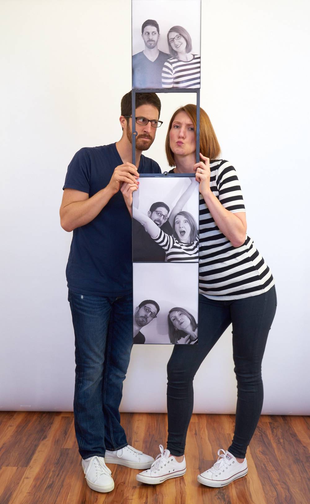 A man and a woman in a black and white striped shirt pose with pictures.