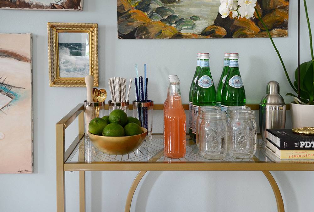 Bottles and fruits sit on a shelf with a glass rack.