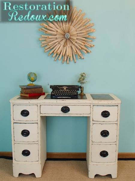 1950's style beige desk has a typewriter and some books on it.