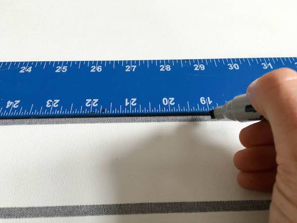 A hand using a pen and ruler to measure out a distance.