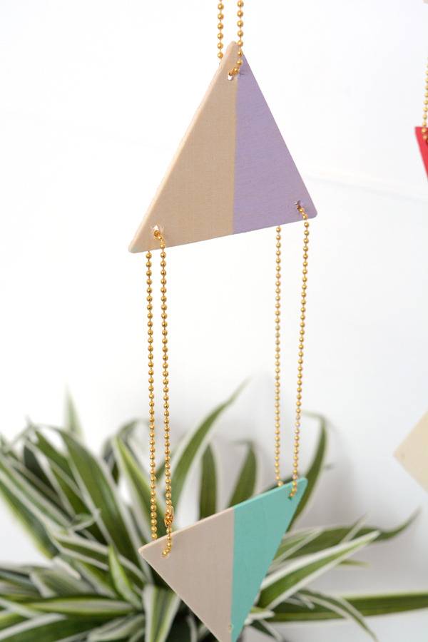 A geometric wooden mobile by a plant.