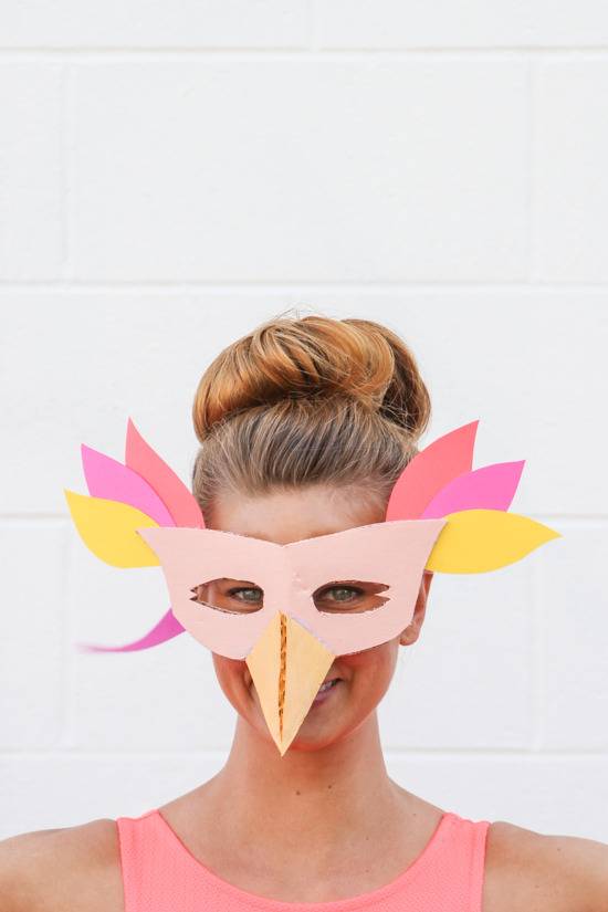 A woman wears a homemade bird mask.