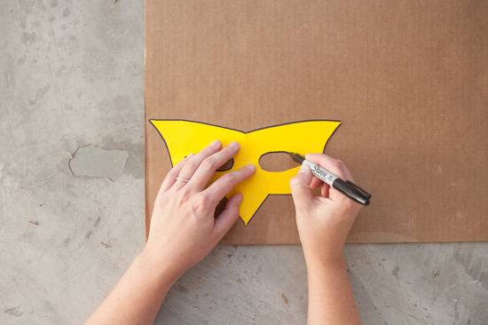 A person traces the outline of a mask on cardboard.