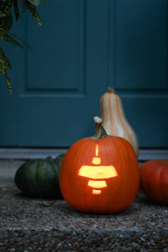 A pumpkin with a pendant light carving.