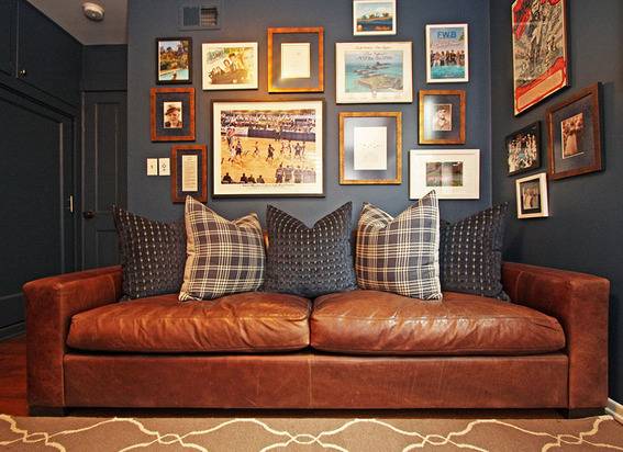 Brown couch with five designer pillows and different wall painting frames on the wall in a living room.