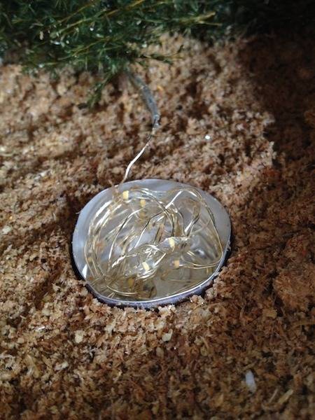 A round metal item is sitting in the dirt.