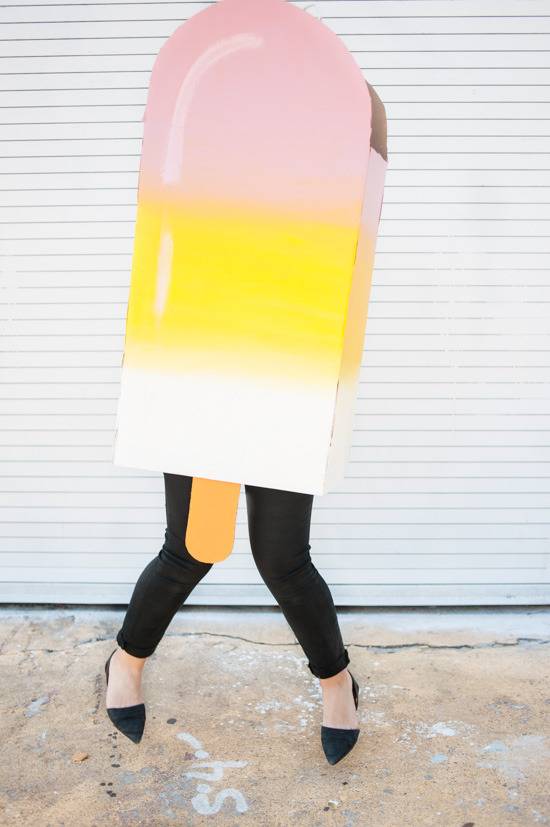 Woman is wearing cardboard popsicle costume for Halloween.