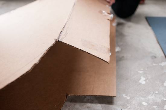 A cardboard box is folded over on a grey surface.
