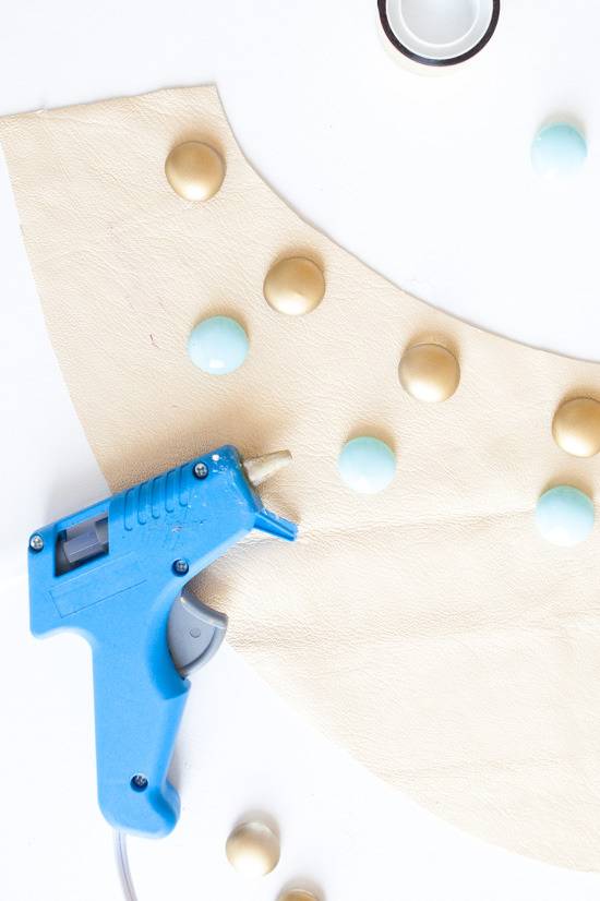 A glue gun is laying on decorative paper and items.