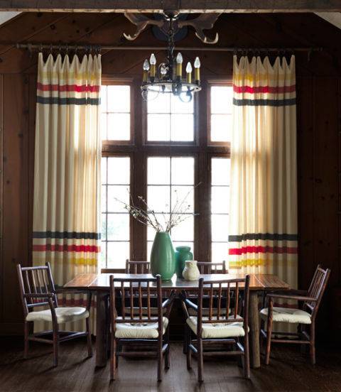 Chairs sit at a table near a large window and under a chandelier.